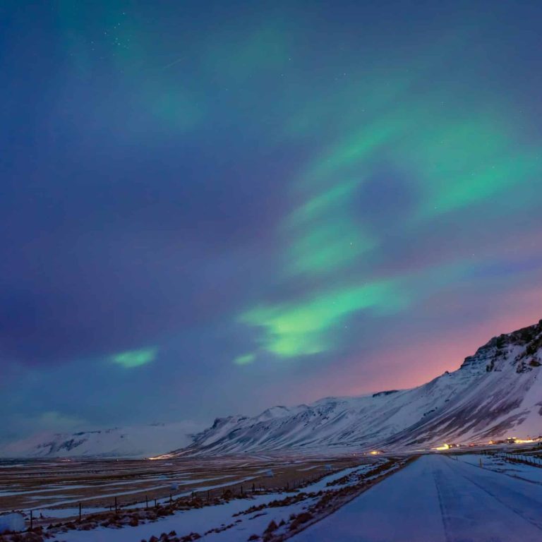 Amazing Northern lights, beautiful view on a colorful sky over high mountains covered with snow, wonderful nature of Iceland
